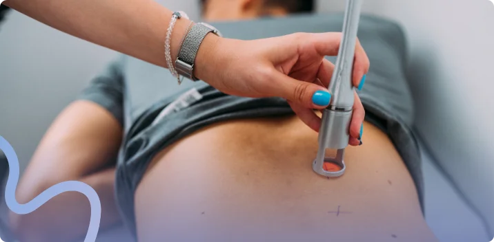 Clinician guiding a handheld Class IV laser therapy device over a patient's skin during treatment