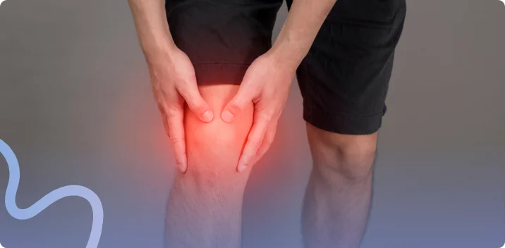 Man in dark shorts gripping his knee with pain highlighted around the kneecap