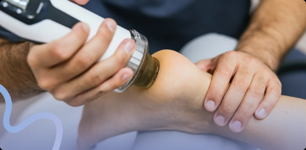 Provider applying a shockwave therapy handpiece to a patient's heel and ankle